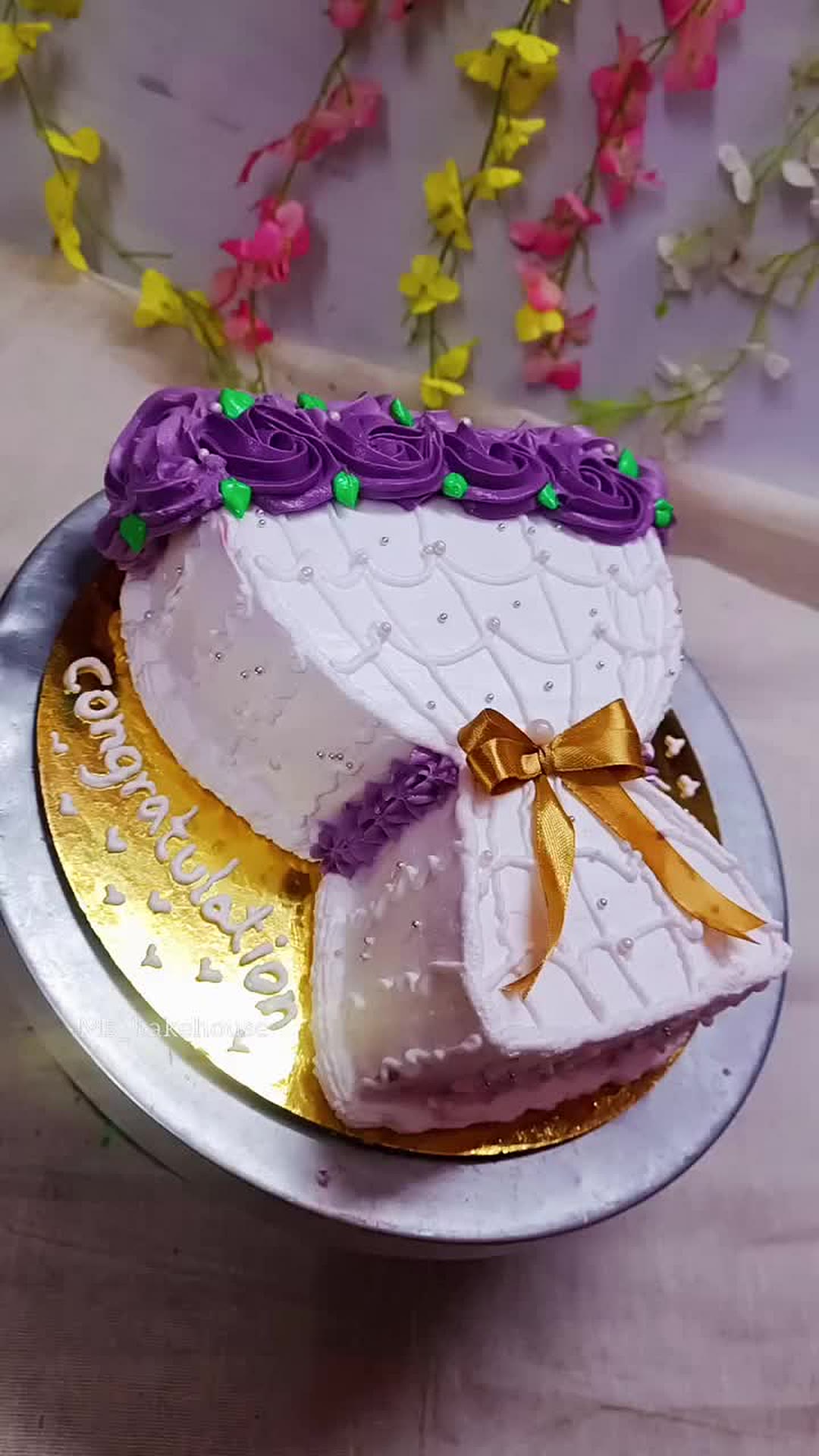Purple and white rosette cake with a gold bow